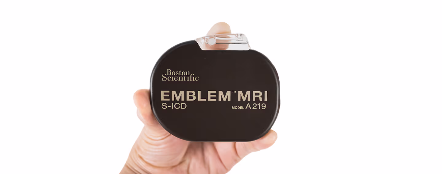 Imagem de um desfibrilador subcutâneo S-ICD EMBLEM™ MRI da Boston Scientific, segurado por uma mão. O dispositivo apresenta um design compacto e inovador para o tratamento de arritmias cardíacas.